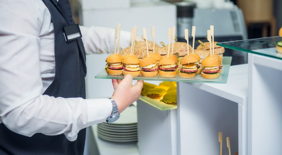 The waiter is serving a catering buffet table with food and snacks for guests of the event.