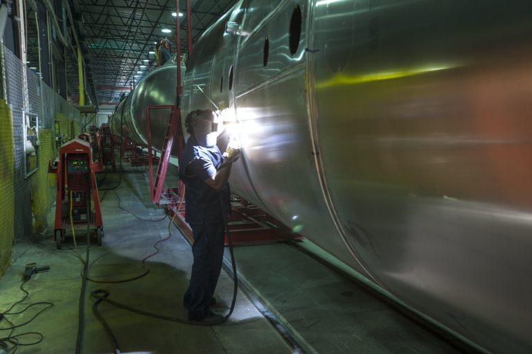 Worker welding large tank in factory